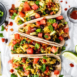 Loaded breakfast tacos full of scrambled eggs and veggies drizzled with hot sauce.