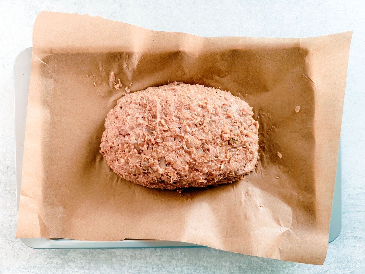 Uncooked ground turkey meatloaf on a baking sheet.