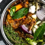 Overhead view of Instant Pot filled with water, colorful vegetable scraps, and roasted chicken scraps.