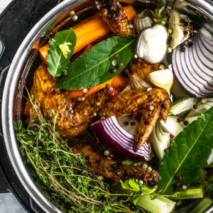 Overhead view of Instant Pot filled with water, colorful vegetable scraps, and roasted chicken scraps.