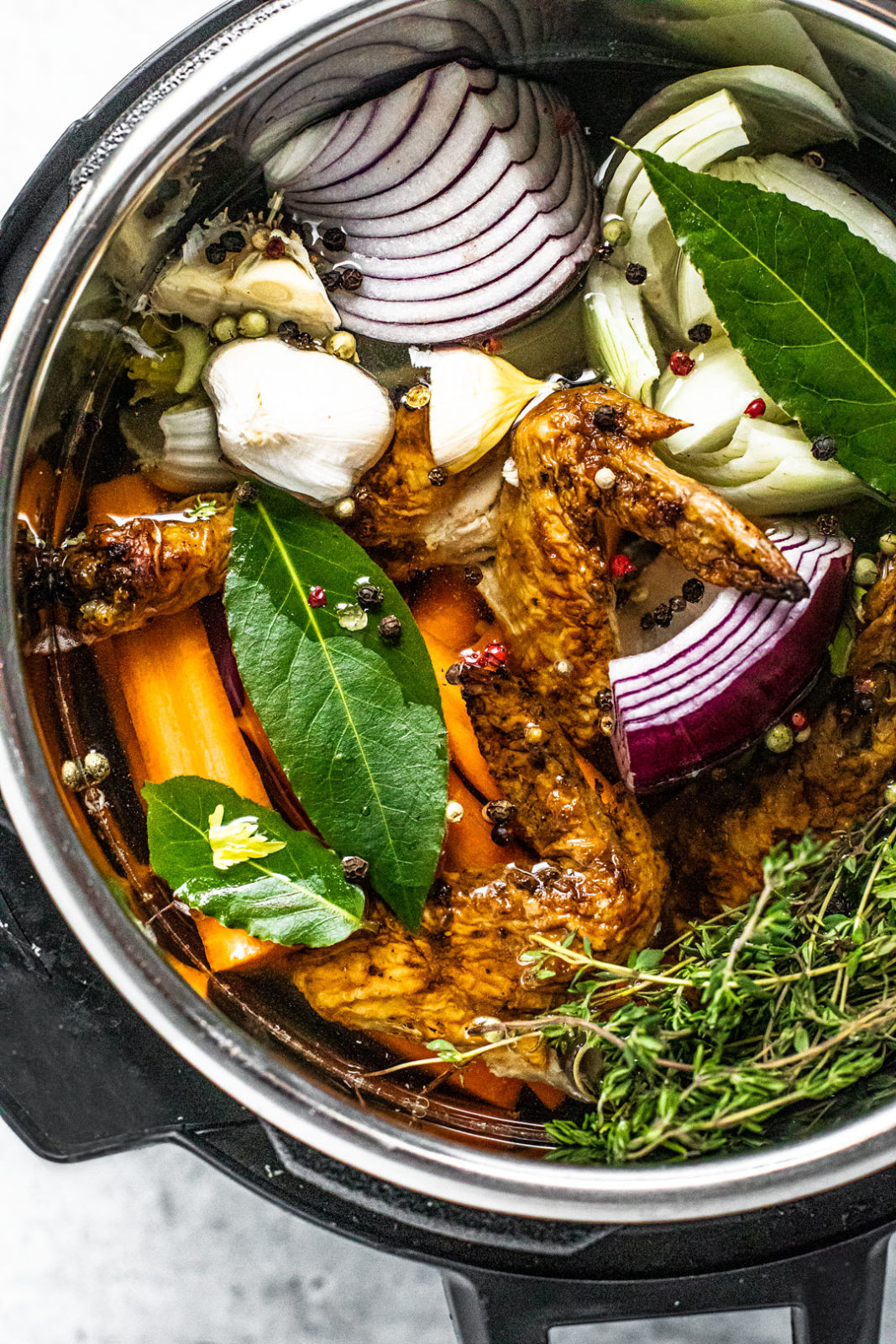 Overhead view of Instant Pot filled with water, colorful vegetable scraps, and roasted chicken scraps.