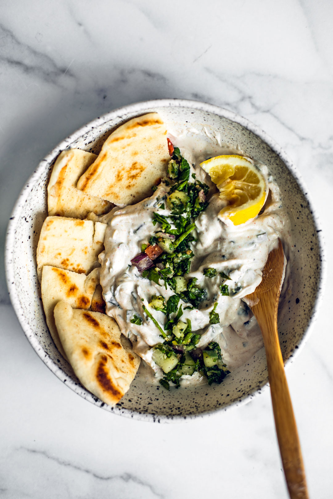 Bowl of mint yogurt sauce for chicken in a bowl with pita wedges.