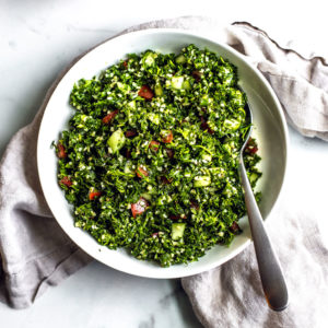 Serving bowl full of freshly made tabbouleh with a serving spoon tucked inside.