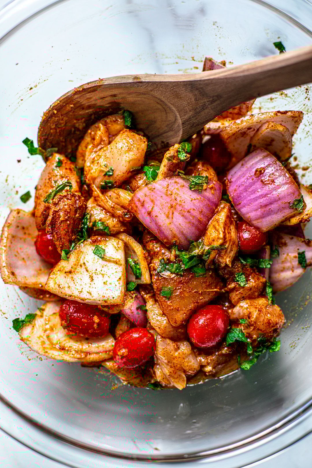 Bowl of raw chicken and vegetables, seasoned with Moroccan seasoning.