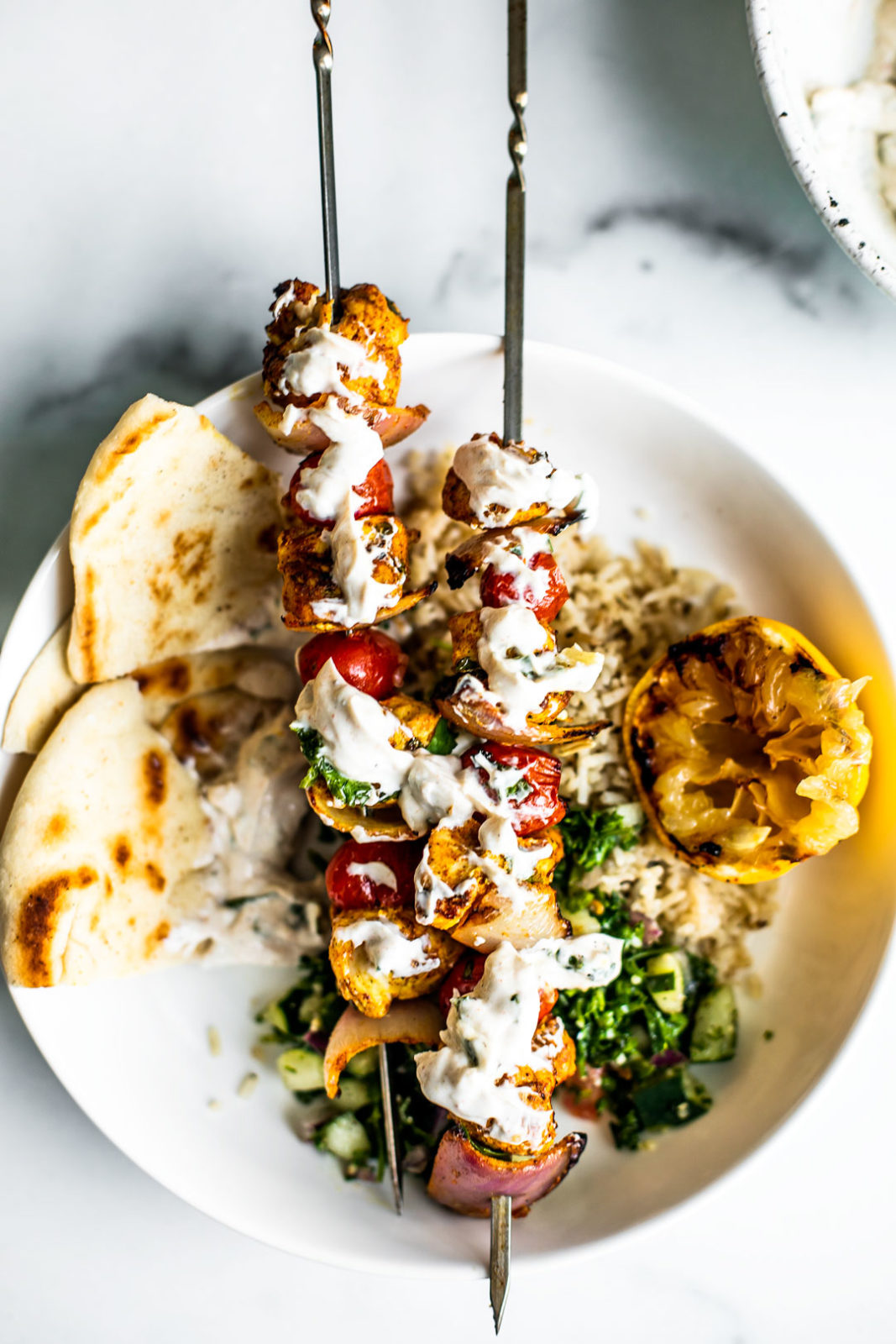 Chicken skewers smothered in Greek yogurt sauce over pitas and rice.