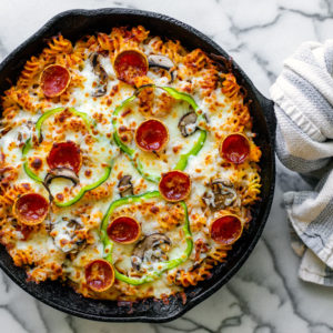 Cheesy pizza pasta bake in a cast iron skillet.