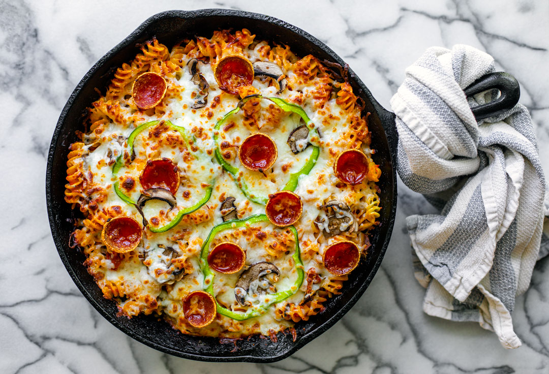 Cheesy pizza pasta bake in a cast iron skillet.