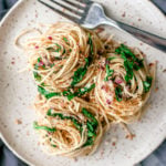 Lemon Pepper Pasta with Sardines twirled onto a plate with bright green arugula.