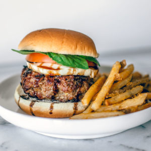 Summer Caprese Burger on a plate with a side of fries.