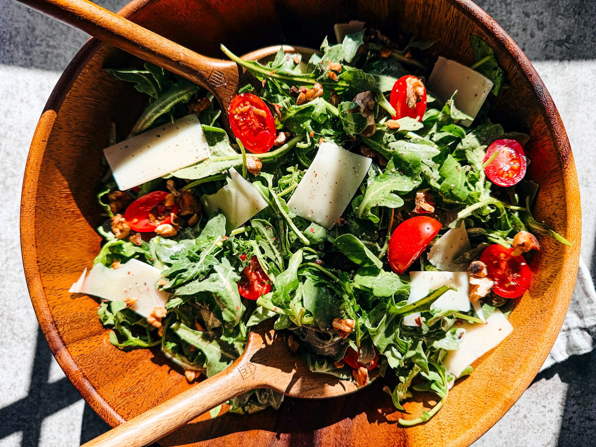 Big wooden serving bowl of arugula salad.