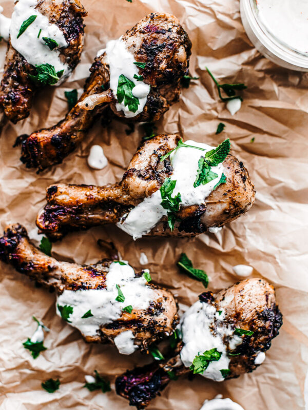 Grilled marinated chicken drumsticks with lemon yogurt sauce, garnished with fresh mint.