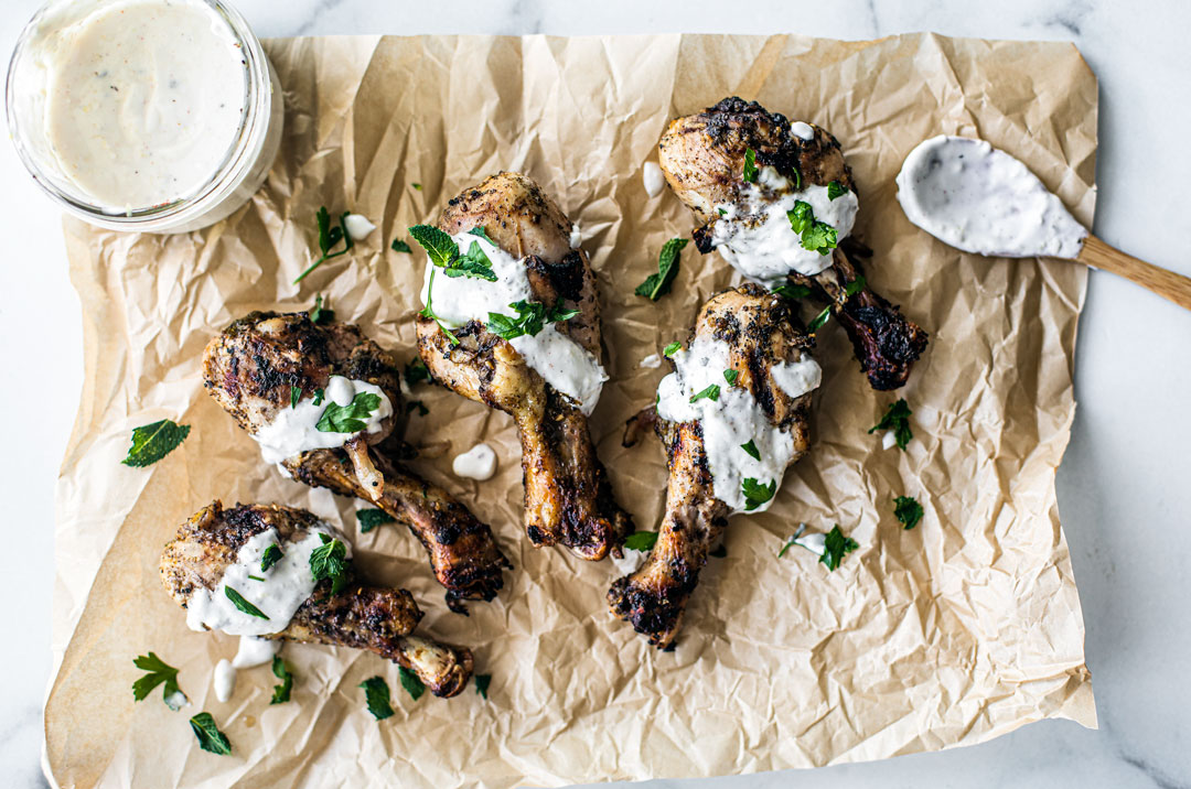 Za'atar Grilled Drumsticks laid out on parchment with lemon yogurt drizzle.
