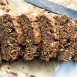Zucchini bread slices lined up with a bread knife.