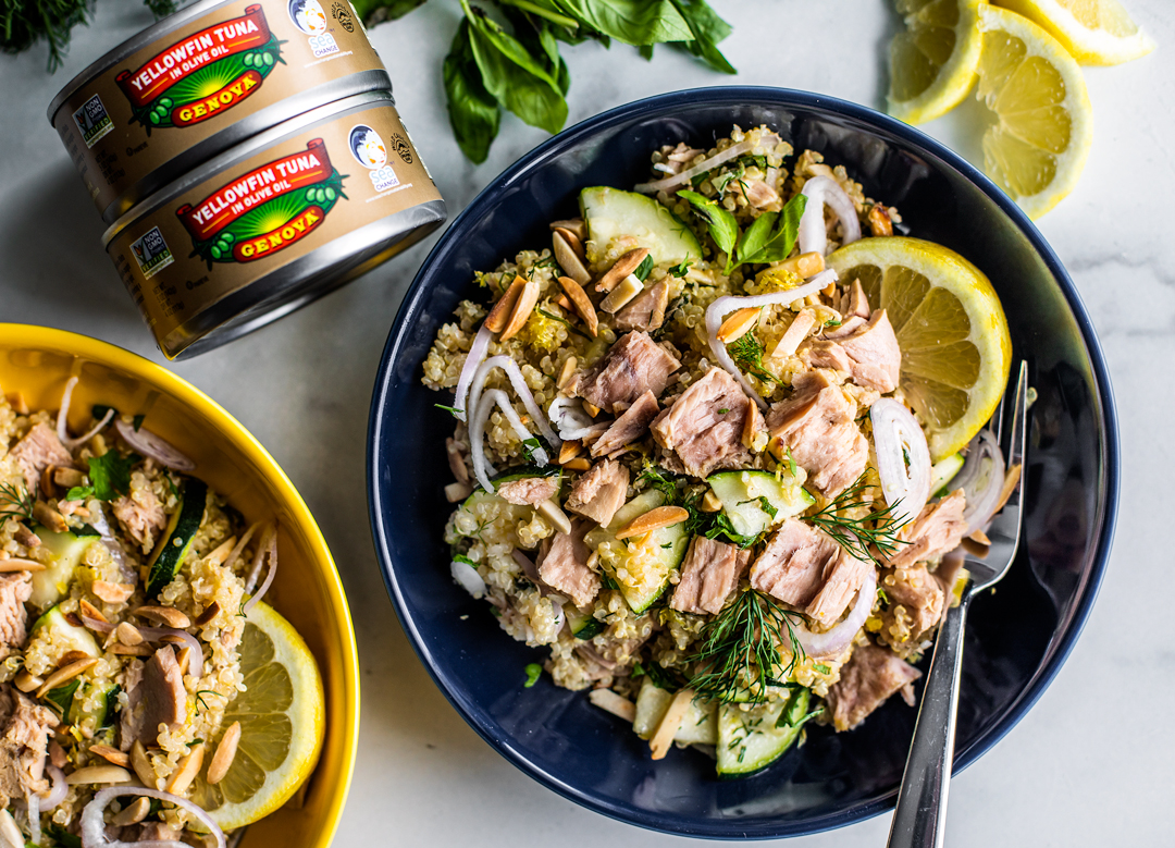 Bowls of quinoa salad with cans of Genova tuna stacked next to them.