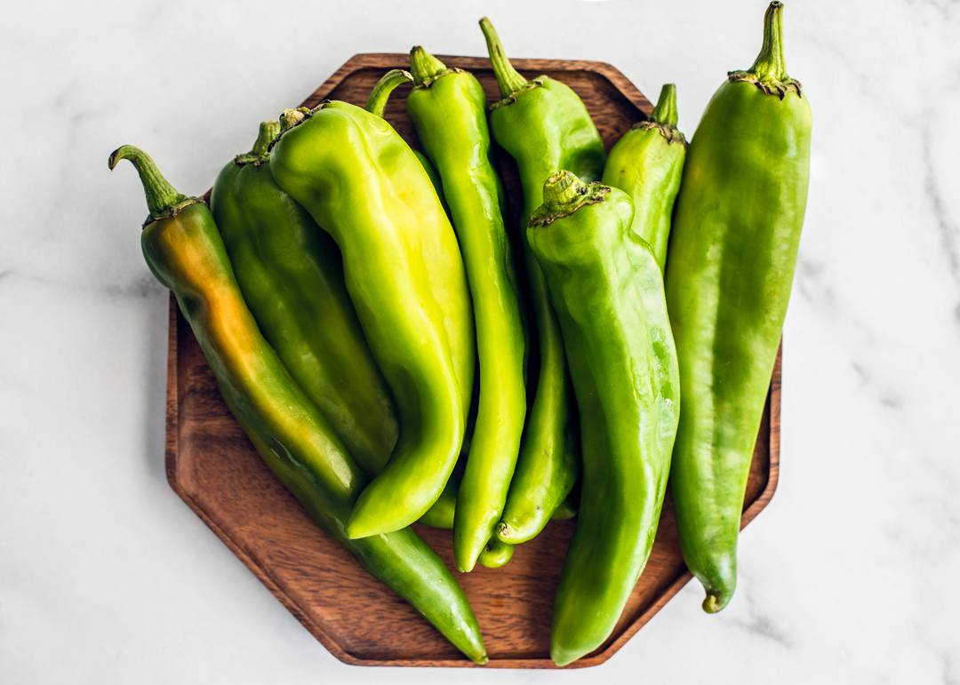 Fresh Hatch chiles on a wooden plate.