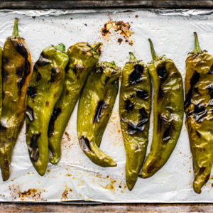 roasted hatch chiles on a baking sheet with foil.