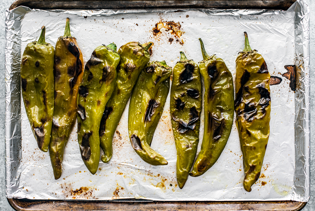 roasted hatch chiles on a baking sheet with foil.