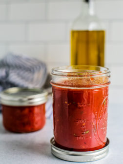 Two jars of homemade pizza sauce on a counter.