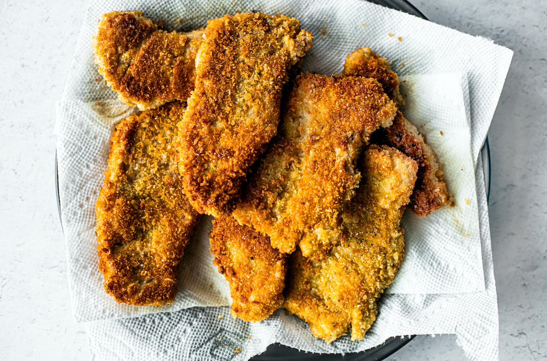 A serving plate piled with crispy breaded pork schnitzel.
