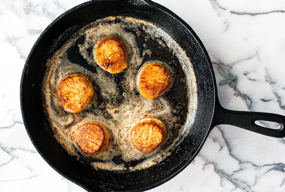 Seared Scallops in a pan with melted butter.
