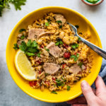 Hand holding up a bowl of Mediterranean Instant Pot Rice with Tuna.