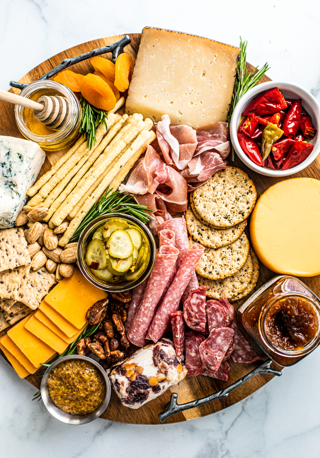 Overhead view of meat and cheese platter with nuts, fruits, jams, honey, etc.