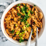 Serving bowl full of shredded buffalo chicken topped with chopped celery.