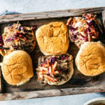 Serving tray with pulled pork sandwiches topped with apple slaw.
