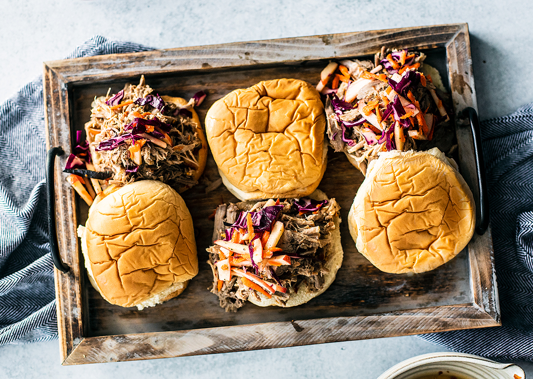 Serving tray with pulled pork sandwiches topped with apple slaw.