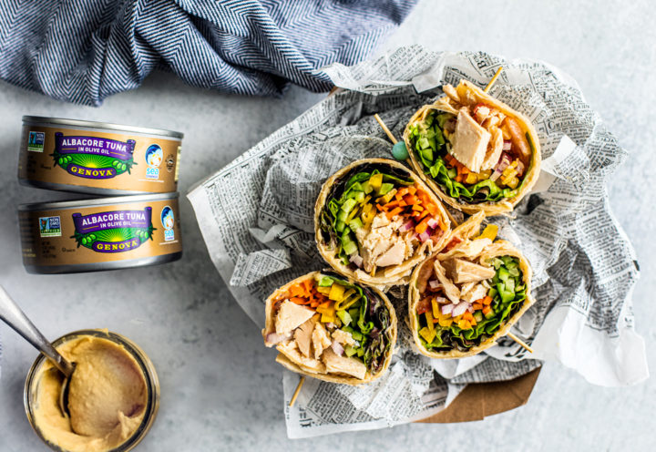 Overhead shot of wraps with jar of hummus and cans of Genova tuna.