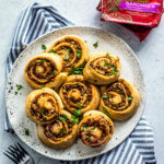 Plate full of Greek Pinwheels with cans of King Oscar sardines on the side.