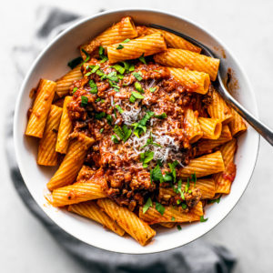 Overhead shot of bowl of rigatoni topped with turkey bolognese.