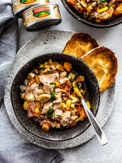 Bowl of ratatouille with tuna on a plate with crusty bread.