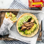 Overhead shot of pita with green goddess dressing, cucumbers, avocado, sprouts, and sardines.