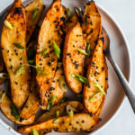 Close up overhead shot of serving plate full of honey miso roasted sweet potatoes with a fork.