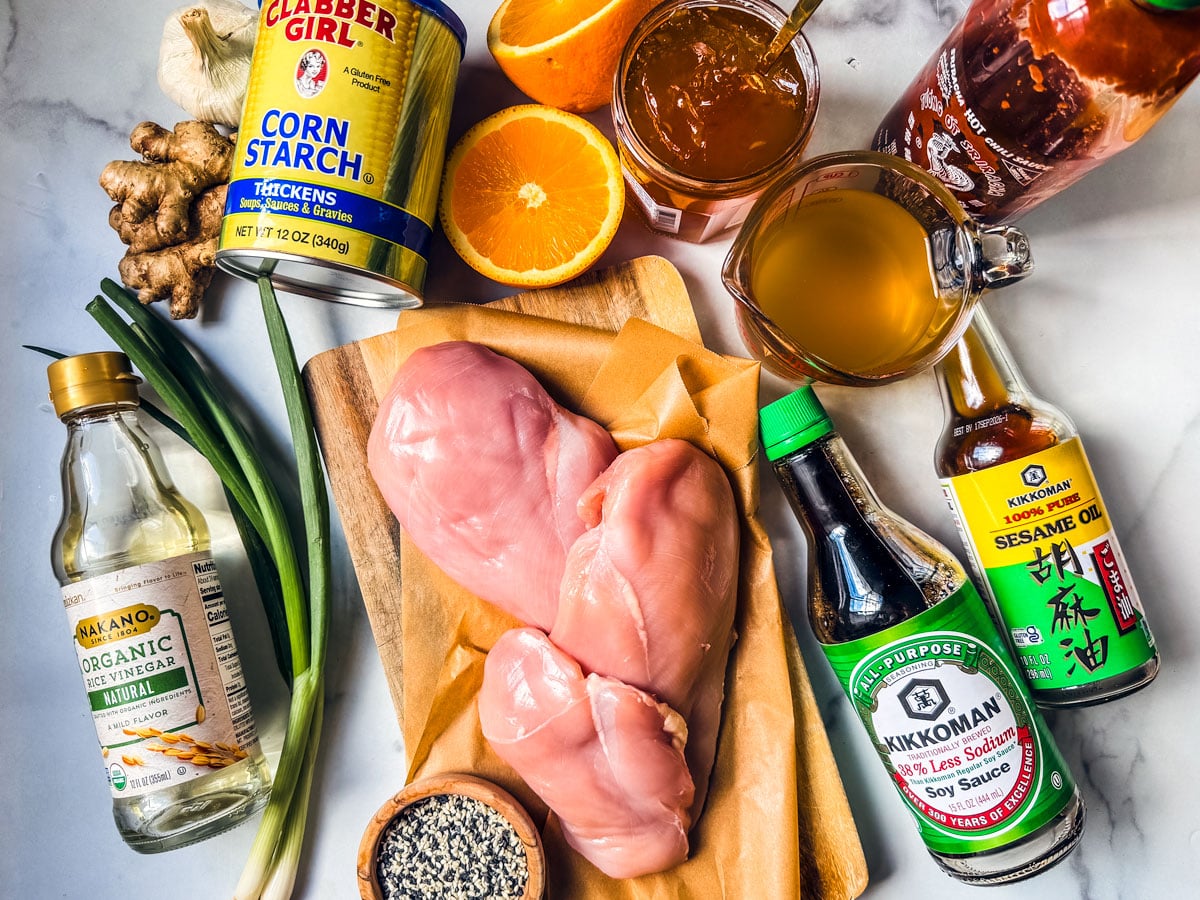 Ingredients for slow cooker orange chicken on a marble countertop.