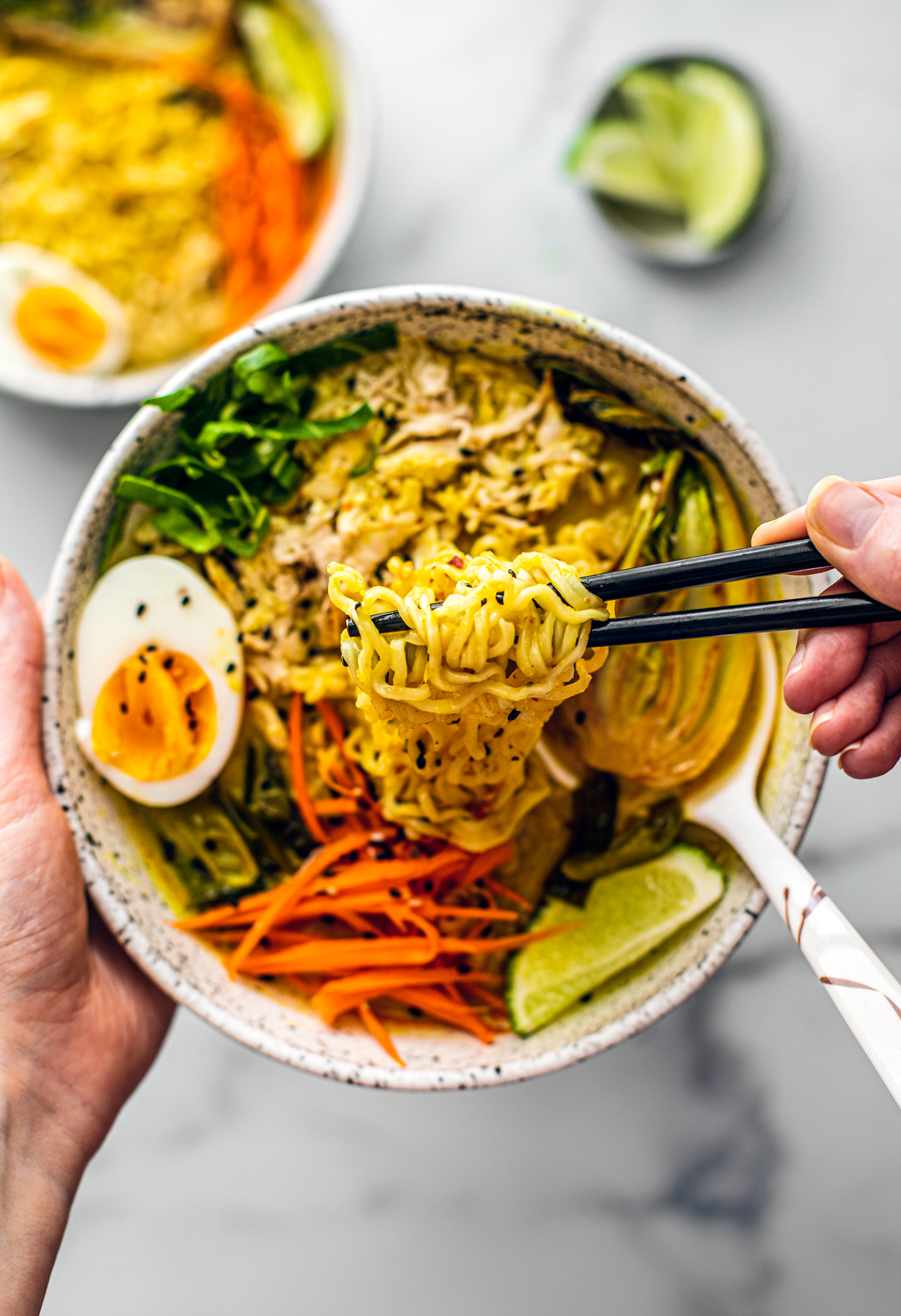 Overhead shot of bowl of chicken curry ramen with chopsticks pulling noodles out of the bowl.