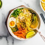 Overhead shot of bowl of chicken curry ramen soup with side of limes.