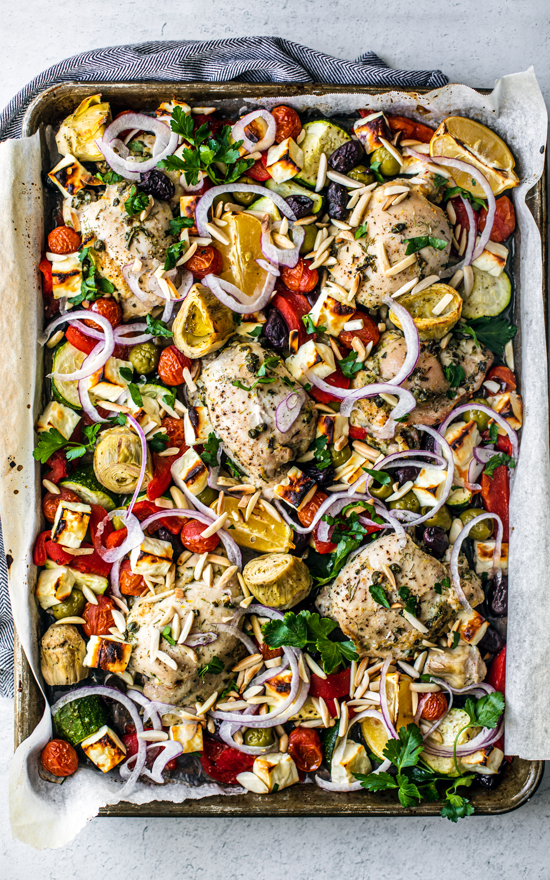 Overhead shot of sheet pan covered with roasted veggies, chicken, and feta.