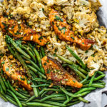 Overhead shot of sheet pan covered in green beans, cauliflower, and glazed salmon.