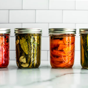 Front shot of jars of quick pickled vegetables lined up.