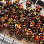 Beef skewers piled up on a baking sheet.