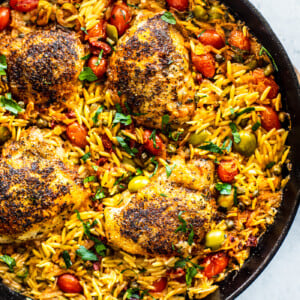 Overhead shot of skillet with orzo, crispy chicken, and veggies.