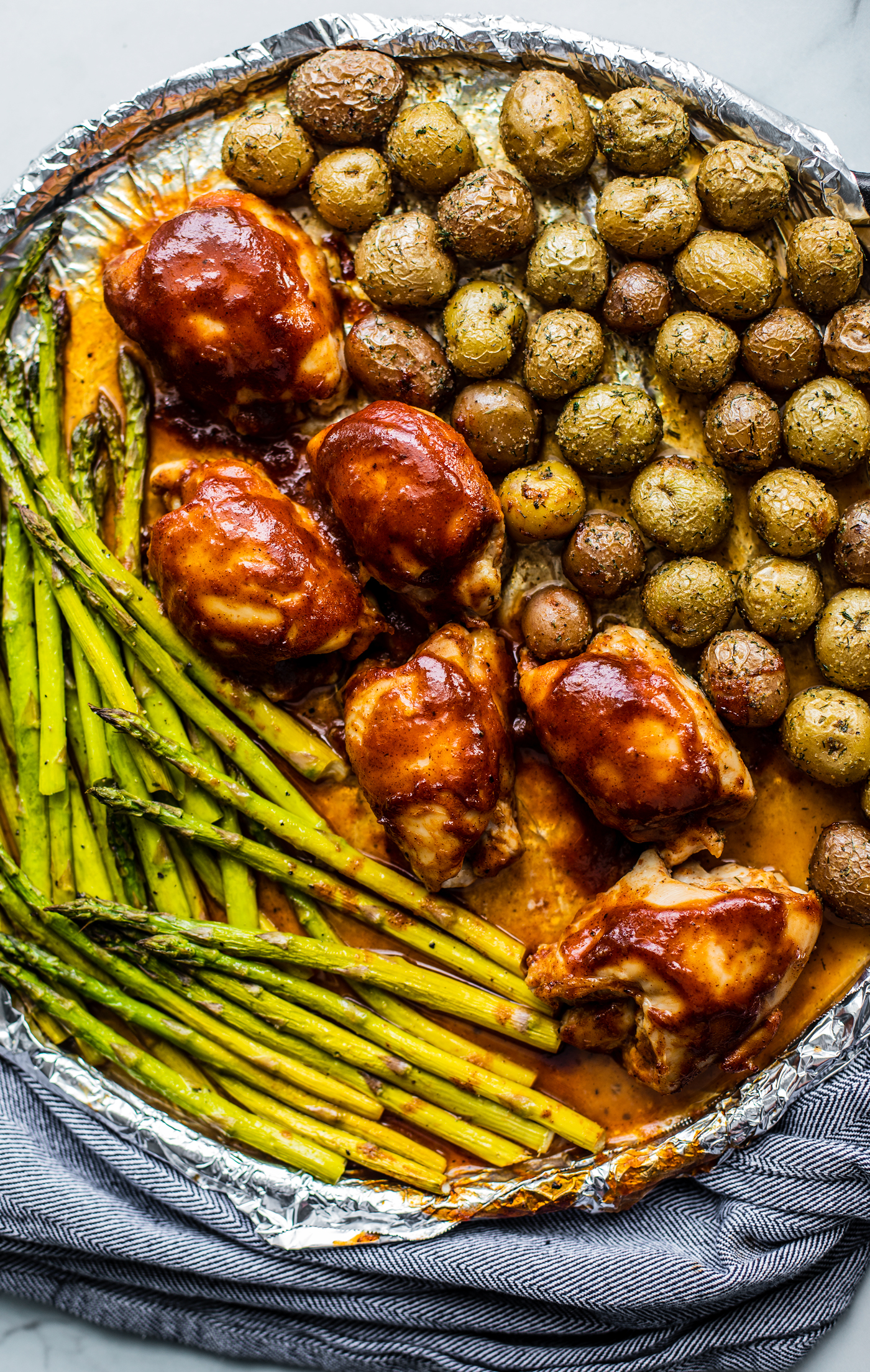 Roasted asparagus, baby potatoes, and BBQ chicken on a sheet pan.