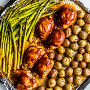 Roasted asparagus, baby potatoes, and BBQ chicken on a sheet pan.