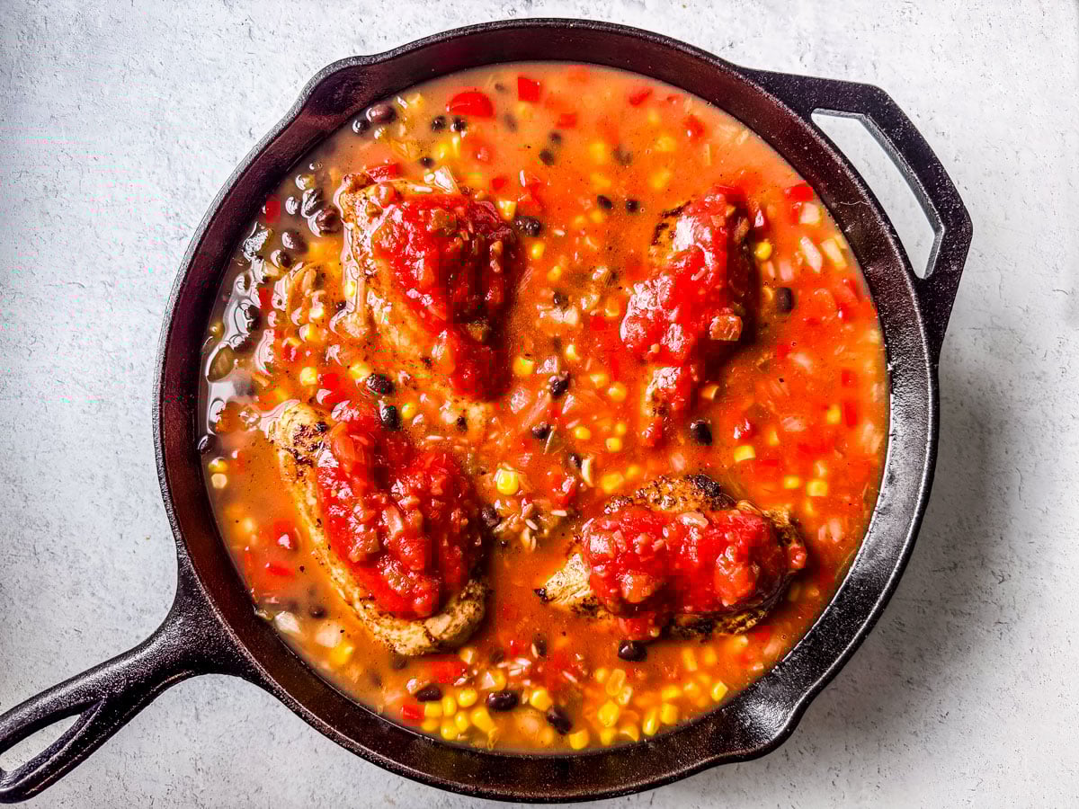 Chicken breasts nestled into the skillet with salsa on top.