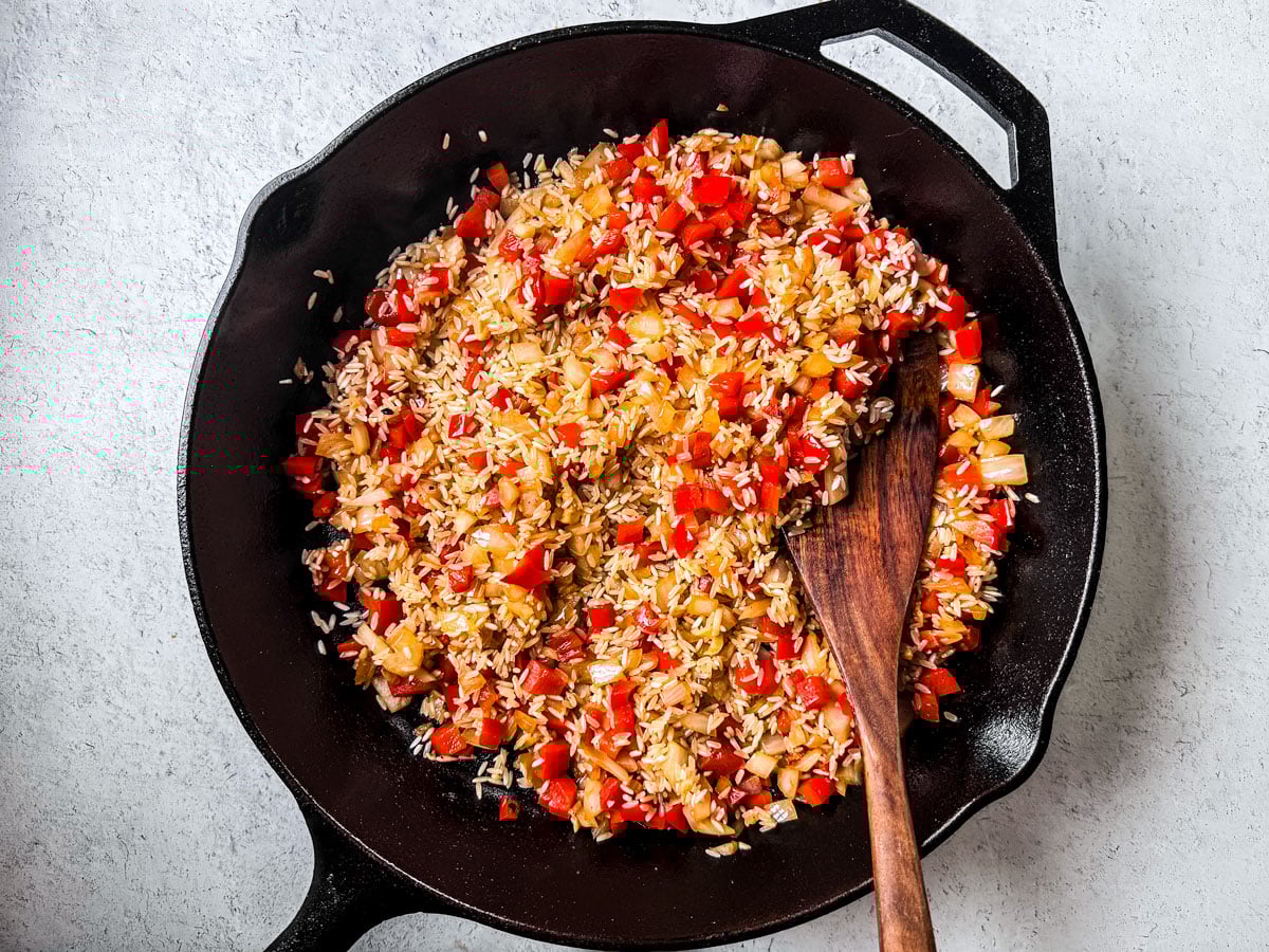 Rice, peppers, and onions in a skillet.