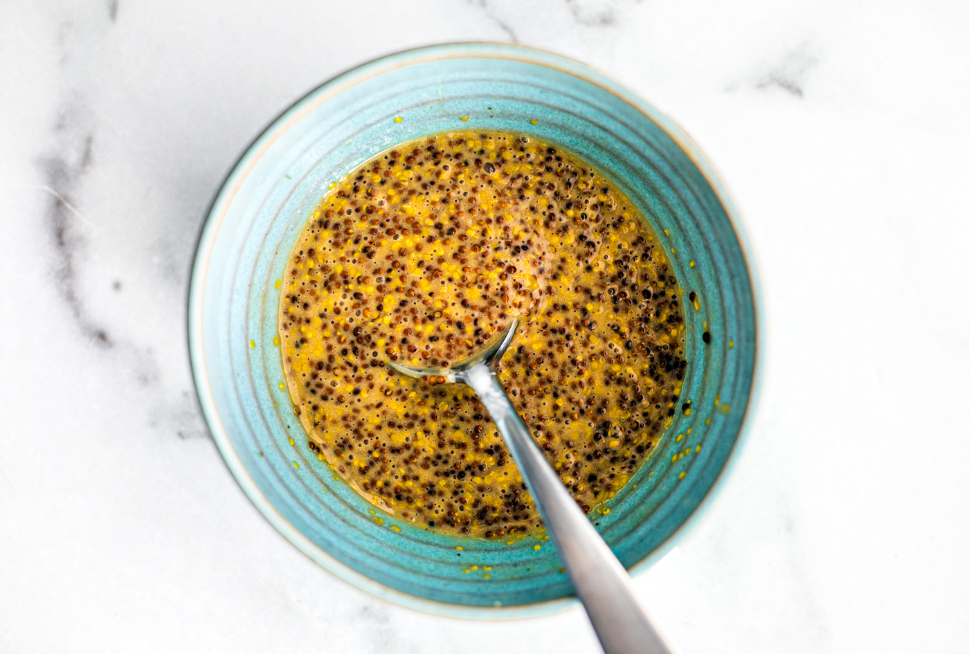 Bowl of sweet and smoky mustard with a spoon in it.