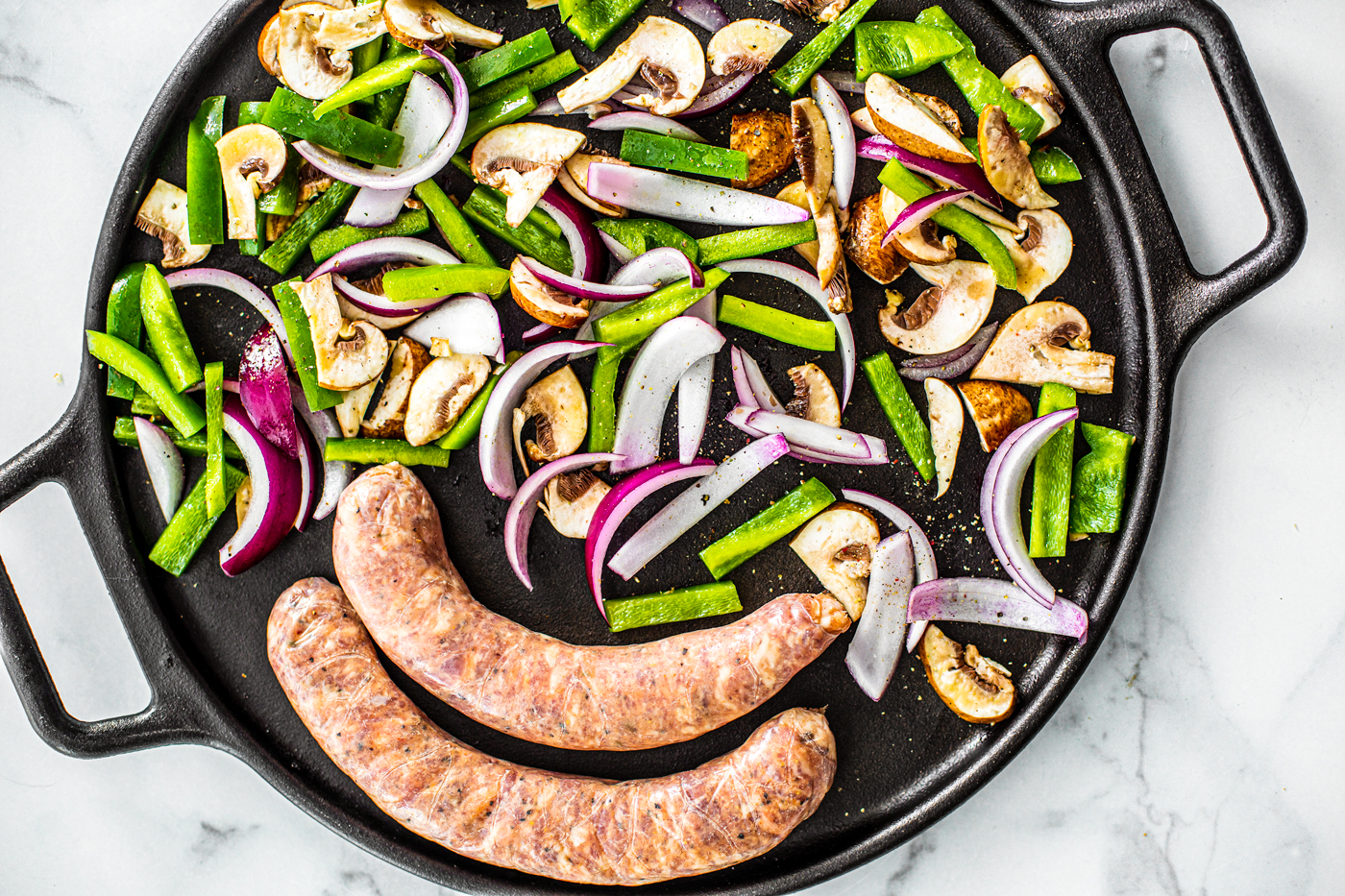 Sheet pan with sausages and cut up bell peppers, onions, and mushrooms.