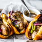 Close up of sausages on buns with veggies.